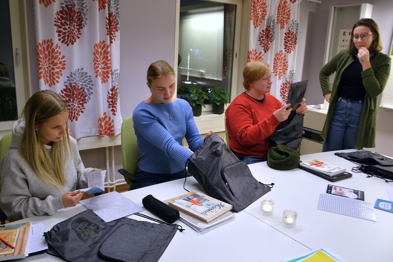 Tilde Svahn, Elvira Ersson och Einar Wanhatalo Bj&ouml;rnstr&ouml;m, gymnasieelever i &Ouml;vertorne&aring;, f&aring;r varsitt exemplar av spr&aring;kpaketet Kielis&auml;kki av Evelina Estola, spr&aring;kfr&auml;mjare vid Spr&aring;kcentrum me&auml;nkieli. Foto: G&ouml;ran Lahti.